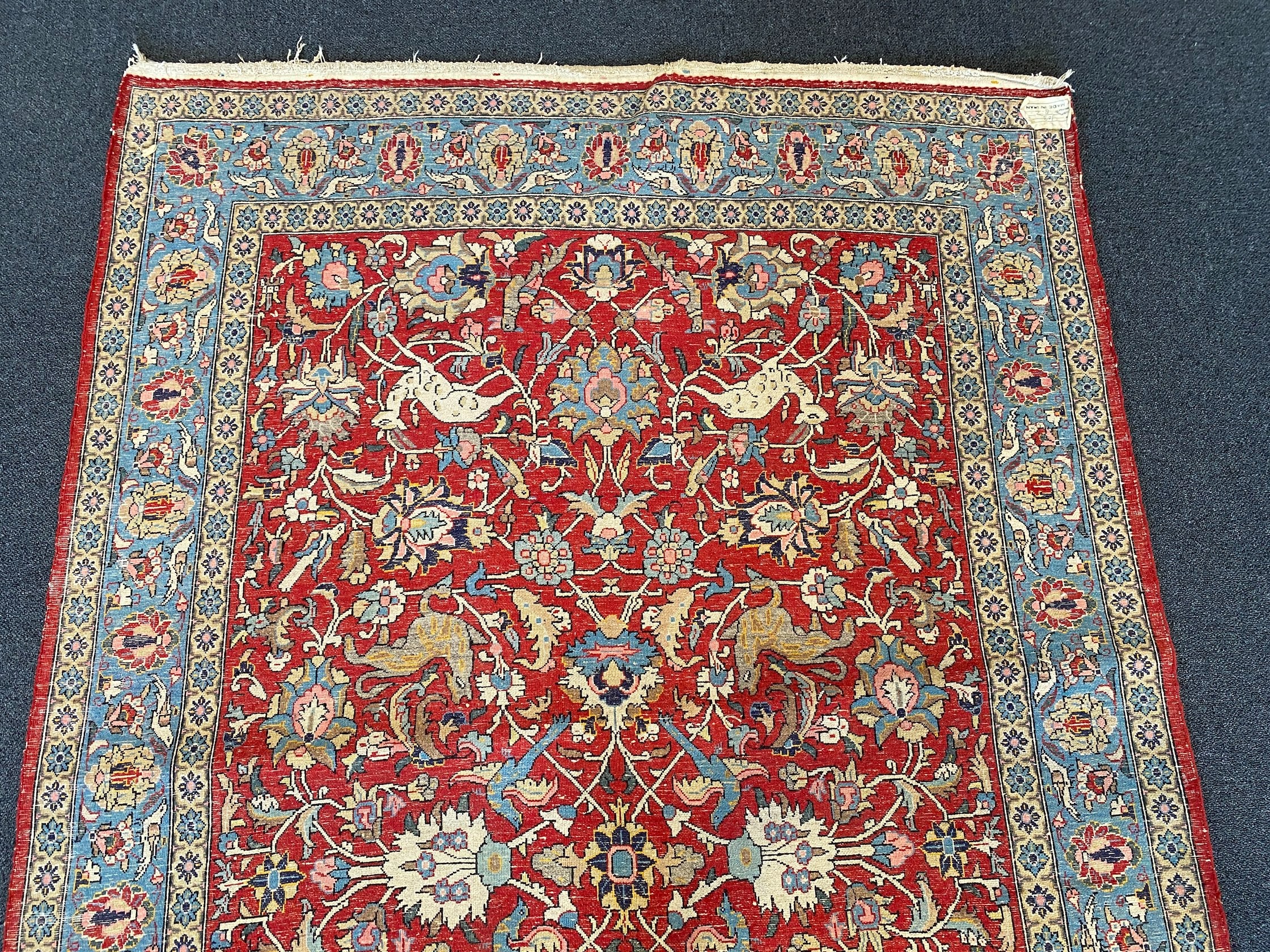 A Persian Qum red ground rug woven with animals and exotic birds among stylised flower heads 220 x 125 cms
